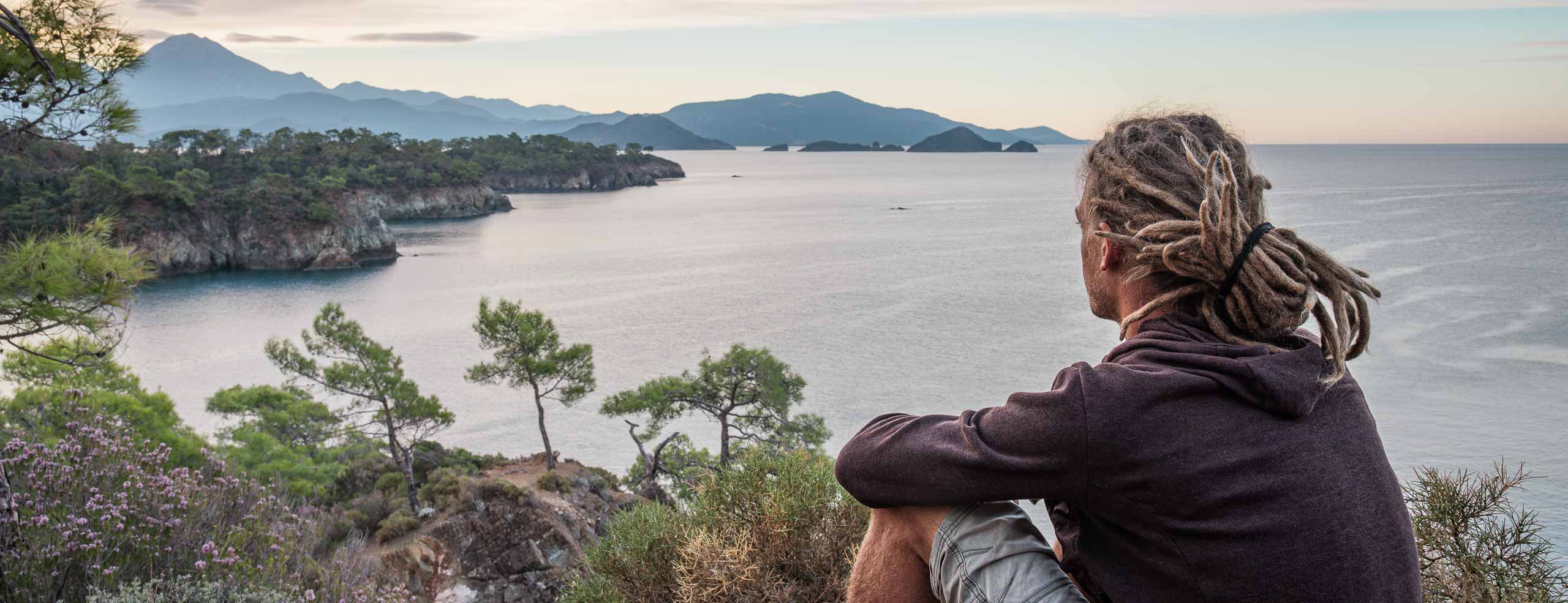 Voyageur à vélo avec des dreadlocks regarde la mer Égée au petit matin, Moment de liberté près de Fethiye, Turquie