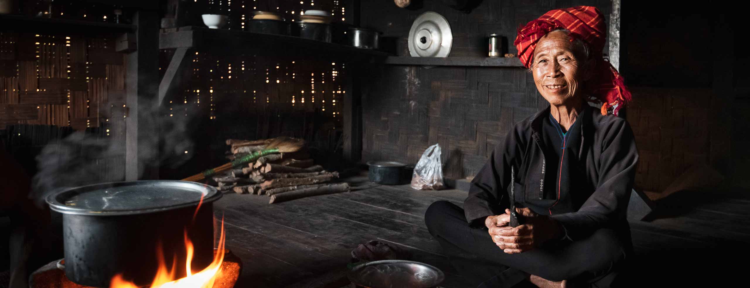 A woman of the Pao ethnic group sits by the fire in her wooden house in Shan State in Burma, Myanmar, Southeast Asia
