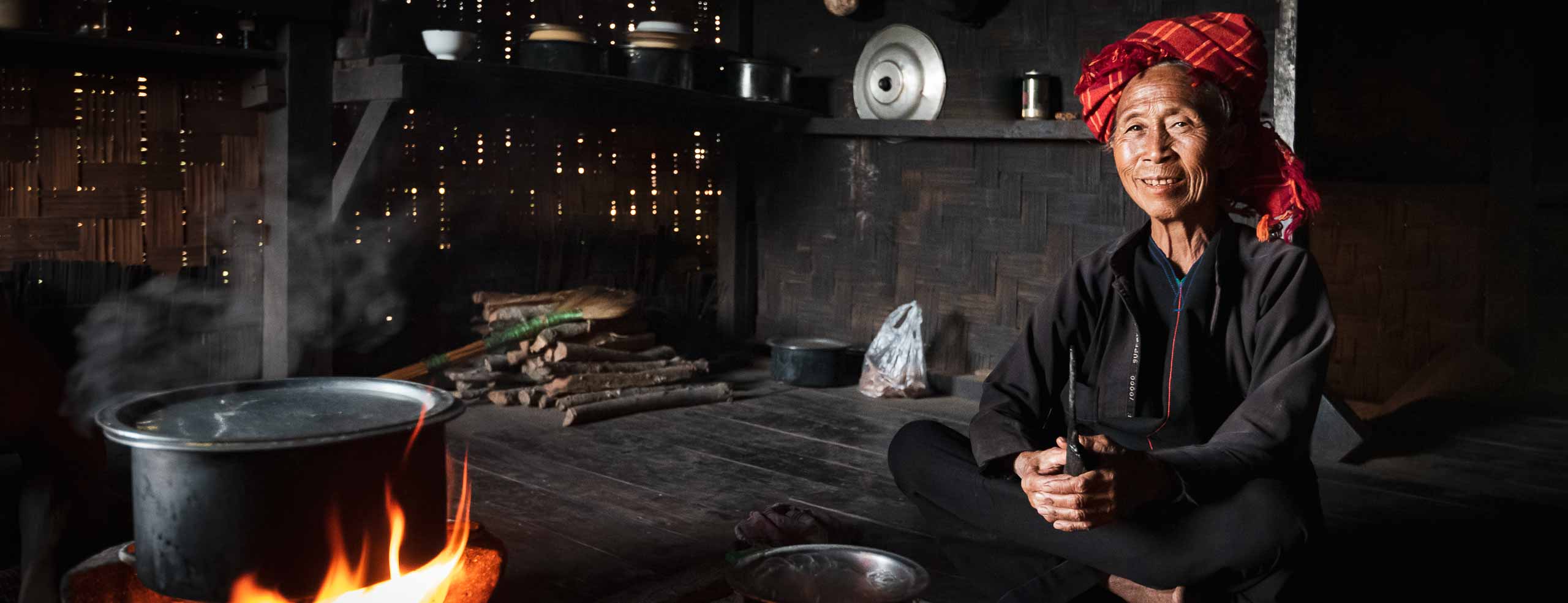 Une femme de l'ethnie Pao est assise près du feu dans sa maison de bois de l'état Shan en Birmanie, Myanmar, Asie du Sud-Est