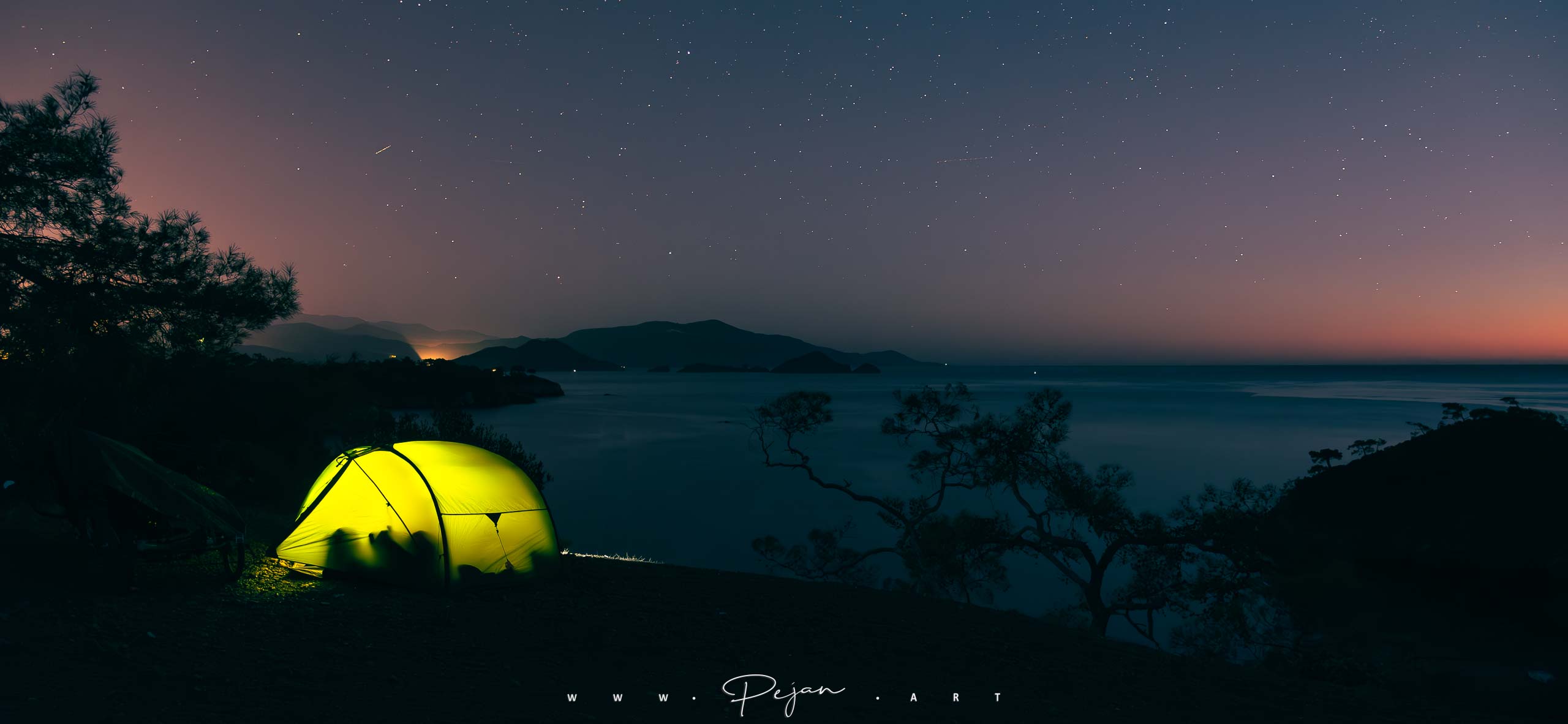Exped Venus II tent illuminated at night on a cliff overlooking the Aegean Sea, bivouac under a star-studded sky near Fethiye, Turkey
