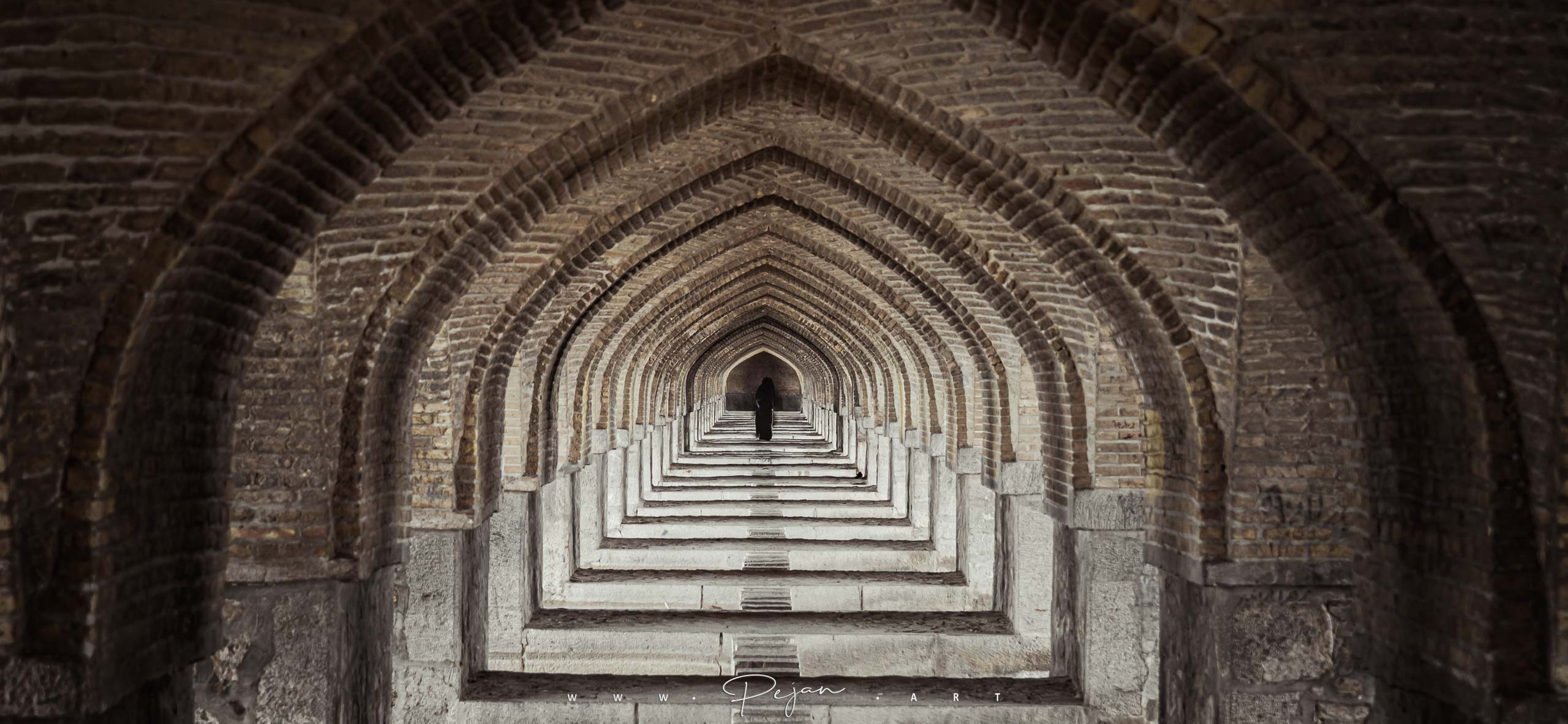 Une femme portant un tchador marche sous le pont Khaju à Ispahan, en Iran. Image iconique. architecture iranienne. Tunnel de portes. Perspective avec point de fuite. répétition.