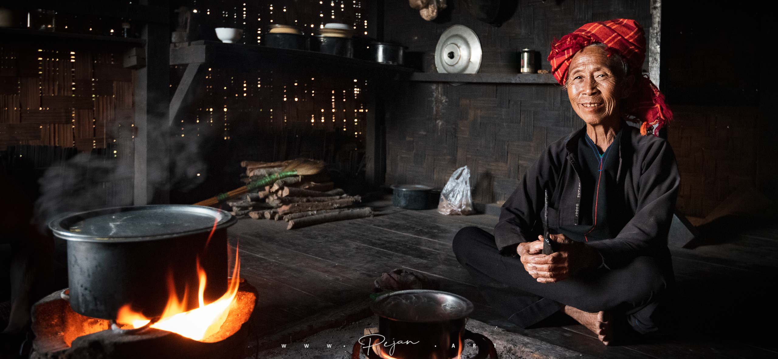 Une femme de l'ethnie Pao est assise près du feu dans sa maison de bois de l'état Shan en Birmanie, Myanmar, Asie du Sud-Est