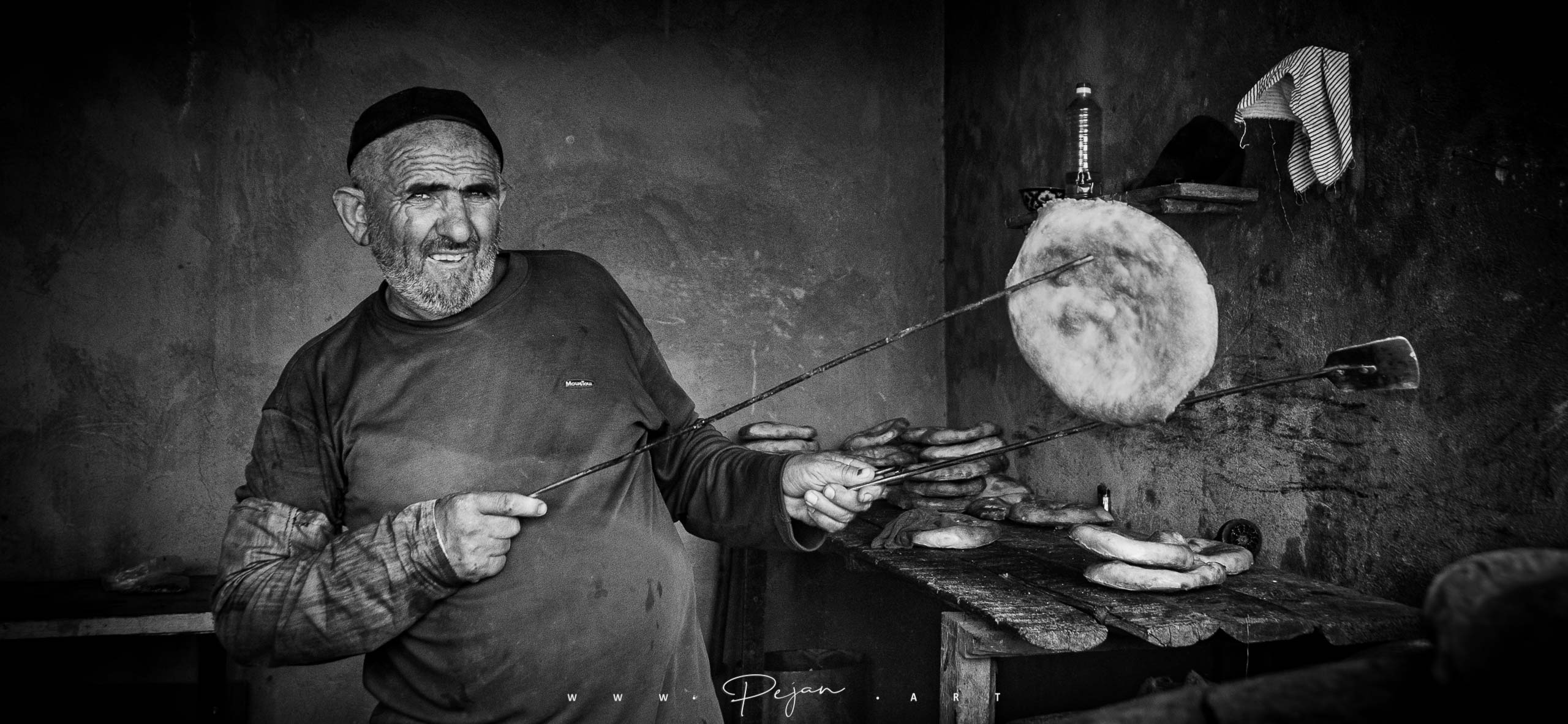 Monochrome portrait of an Uzbek baker presenting a typical Central Asian round bread, Sukhan-Darya, Uzbekistan