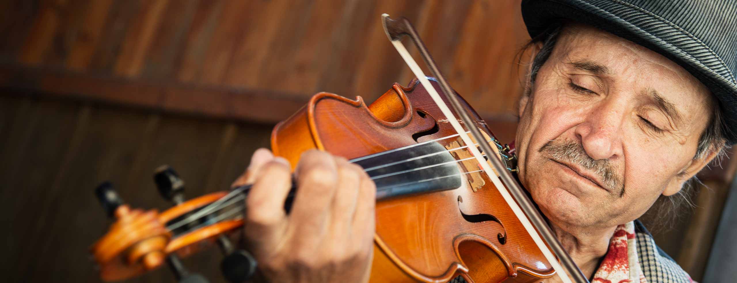 Portrait d'un violoniste Tzigane à Rosia Montana dans les monts Apuseni, en Roumanie. L'homme porte un chapeau traditionnel et joue du violon. Les yeux fermés, il semble emporté par la musique.