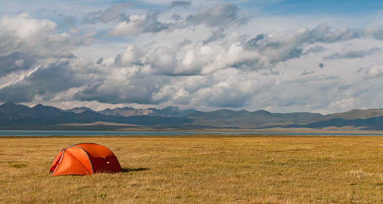 Bivouac in immense nature in Central Asia - A red tent in the Tian Shan mountains, near Song Kul lake, Travel to Kyrgyzstan, Central Asia