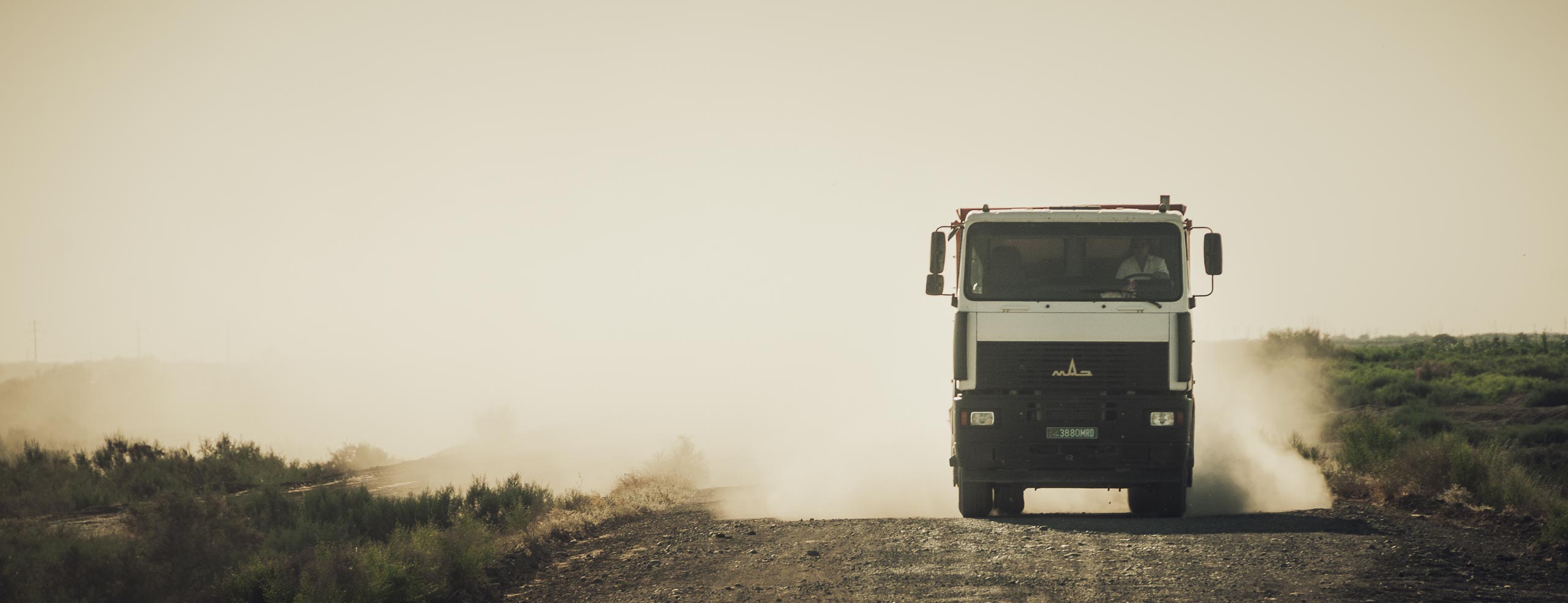 Camion sur une route poussiéreuse du Turkménistan en Asie Centrale, l’atmosphère semble couverte de poussière - Un voyage à vélo à travers l'Asie
