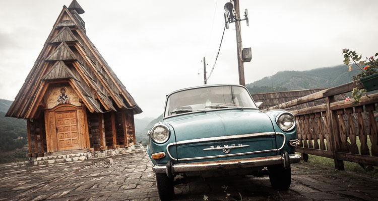 Une ancienne Skoda bleue et une chapelle Orthodoxe en bois dans les montagnes de l'ouest de la Serbie, à Mokra Gora, près de la frontière bosniaque.