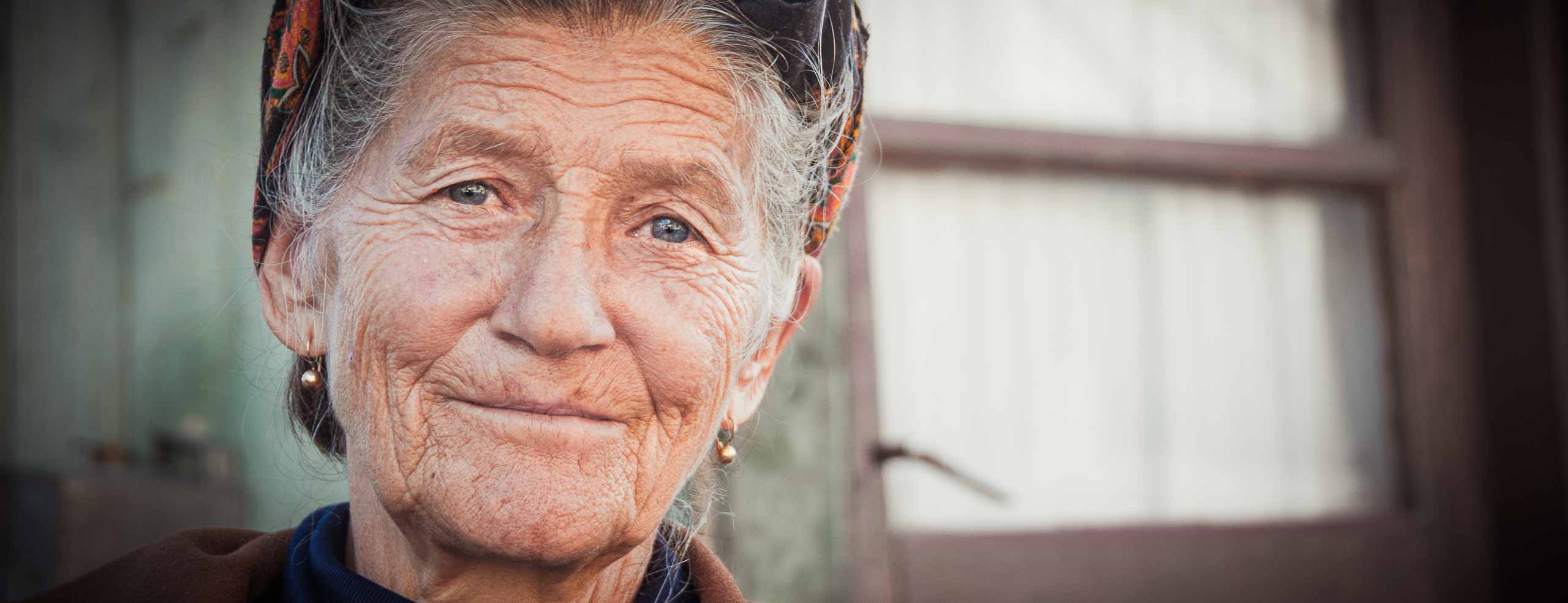 Portrait d'une femme roumaine, habitante des Carpates près de la route Transfagarasan. Elle porte porte le traditionnel fichu et sourit en regardant l'objectif