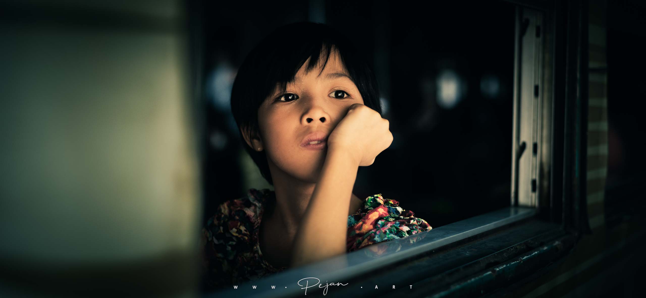 Portrait d'une jeune fille qui regarde par le fenêtre d'un train à Yangoon en Birmanie, Asie du Sud-Est. Elle a l'air d'être perdue dans ses pensées.